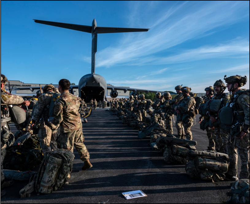 Soldiers in uniform in the foreground with a grounded military aircraft in the backround.